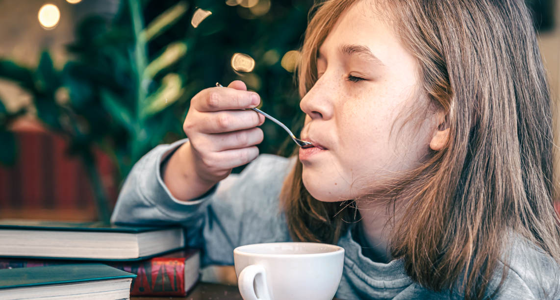 A little girl enjoys tea while sitting in a cafe.